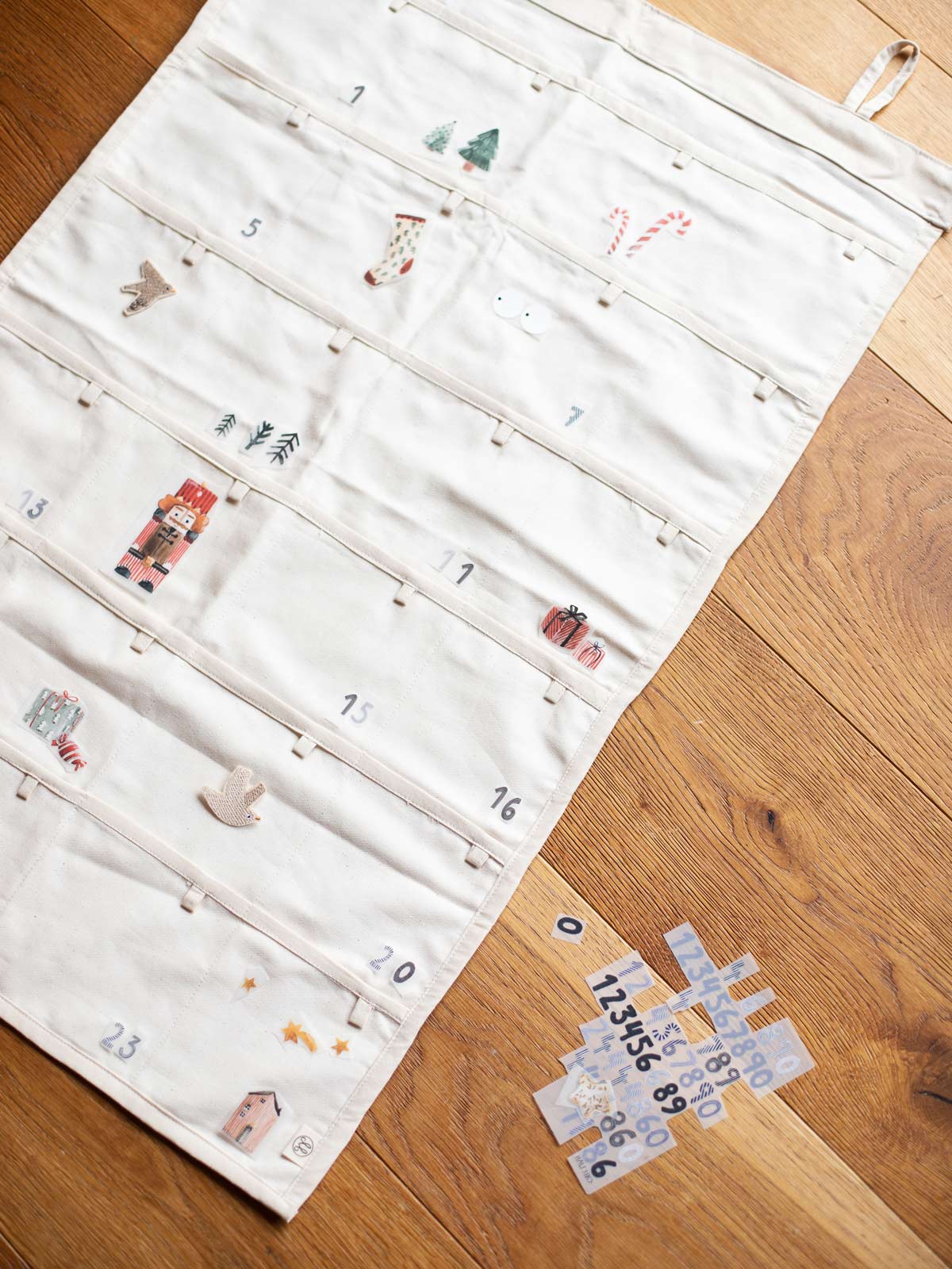 Adventskalender aus beigem Stoff mit Taschen, bebügelt mit Weihnachtsbügelbildern und Zahlenbügelbildern von Halfbird