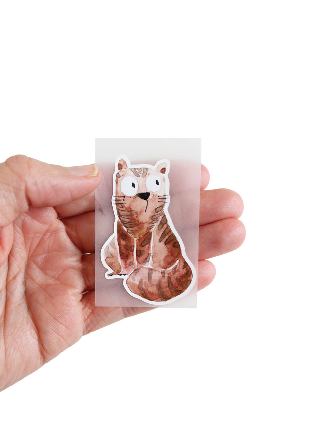 In der Hand liegt ein Bügelbild von halfbird motiv sitzende Katze in braun