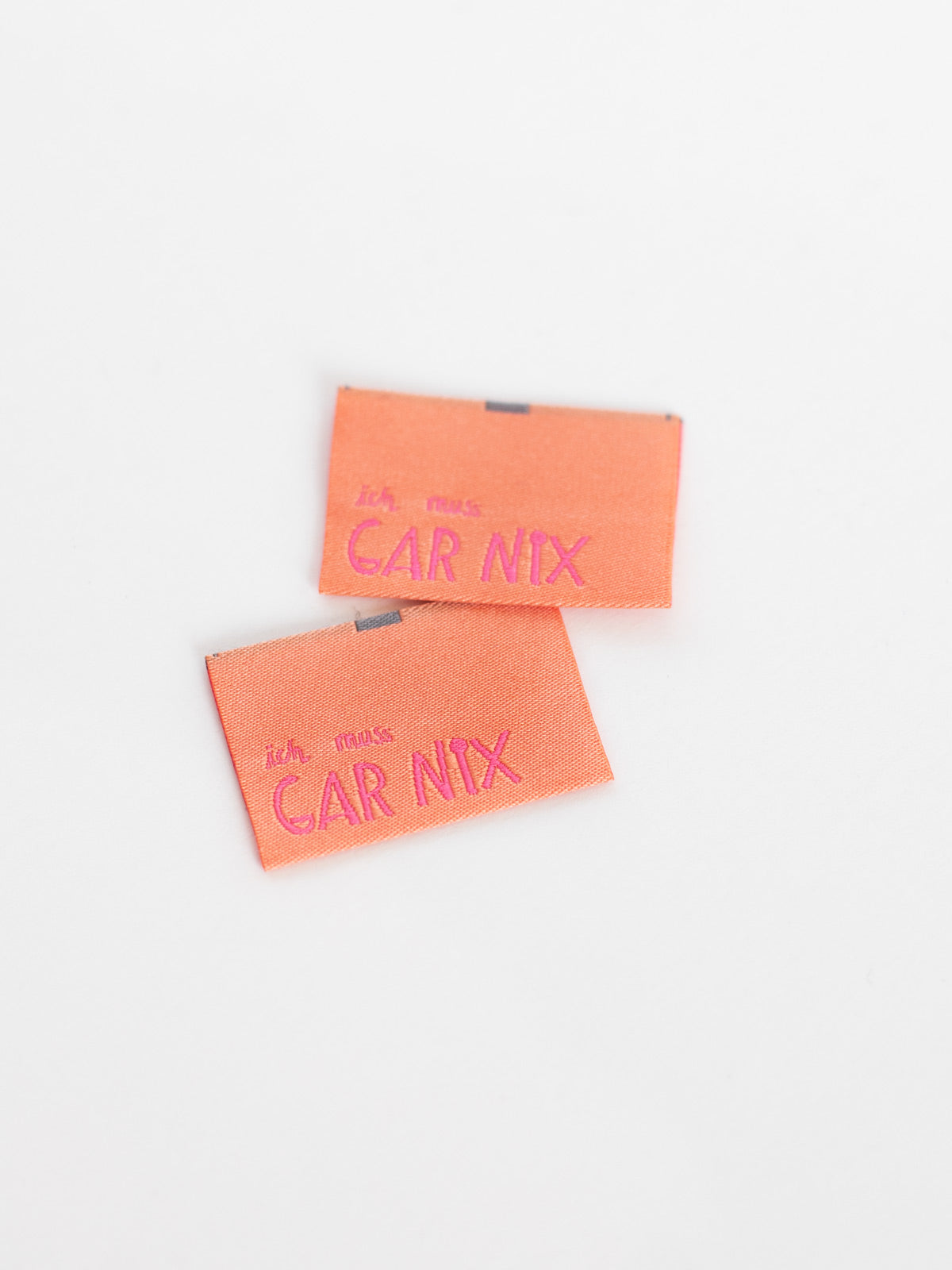 apricotfarbene Nähetiketten mit der neonpinken Aufschrift "ich muss gar nix" von Halfbird