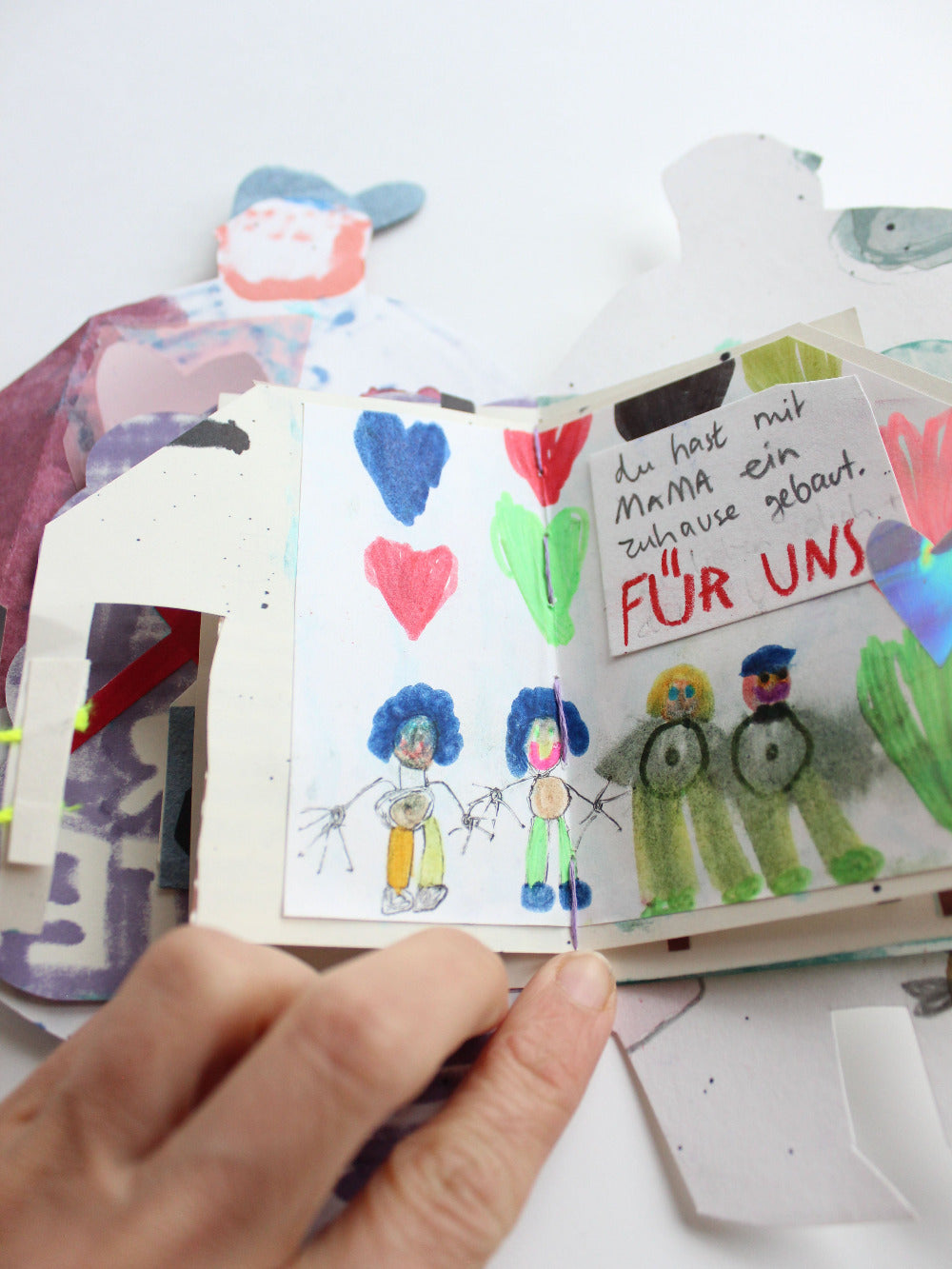 Aufgeschlagenes Superkräftebuch von Halfbird mit Haus-Seite und dem darauf geschriebenen Text "Du hast mit Mama ein Zuhause gebaut für uns"