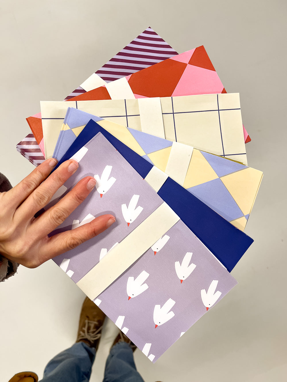 Hand mit Geschenktüten in unterschiedlichen Farben und Mustern von Halfbird