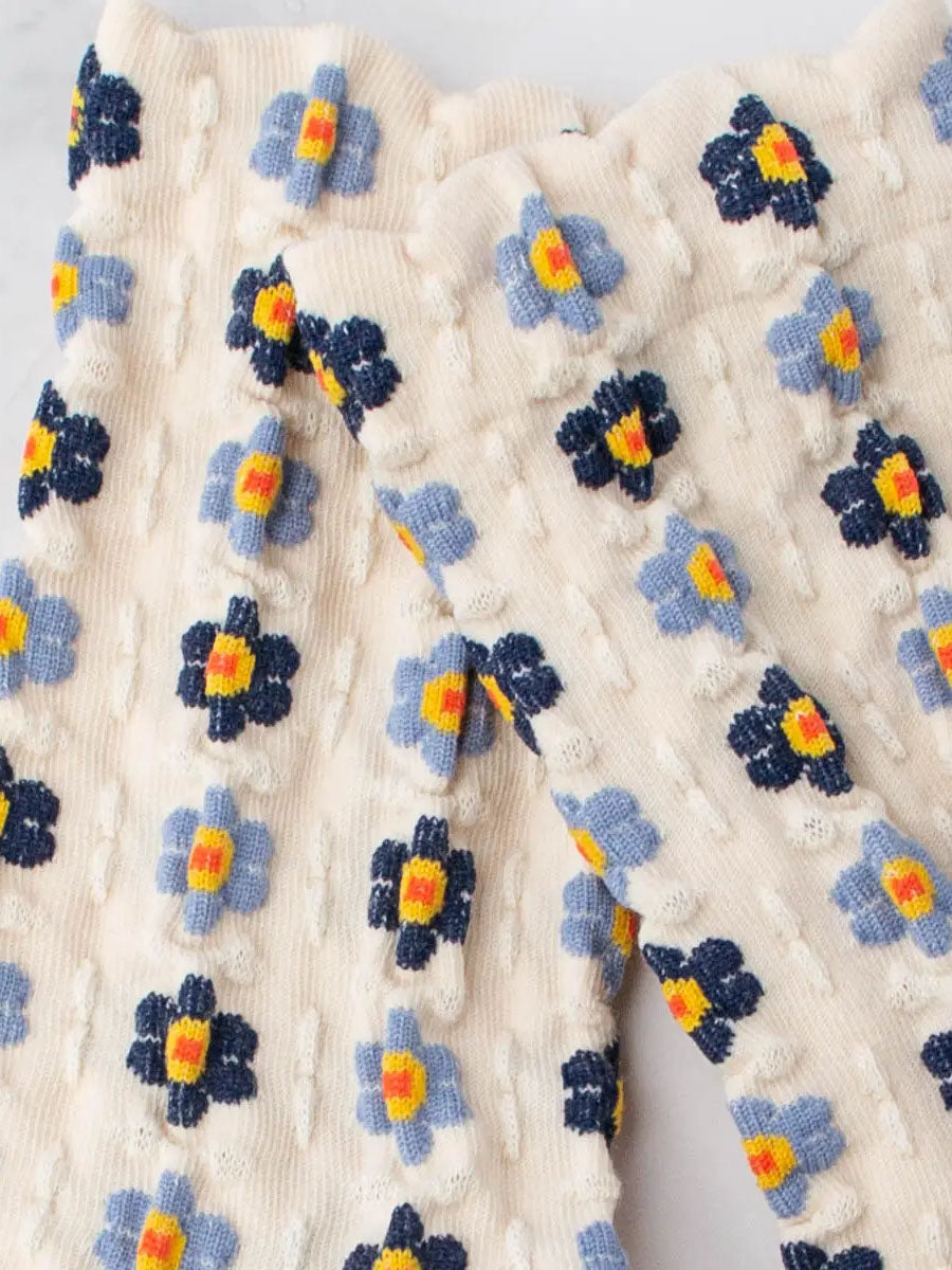 Detailansicht von Cremefarbenen Socken mit Stickerei Anmutung und hellblauen und dunkelblauen Blumen mit gelb/roten Blütenstempeln