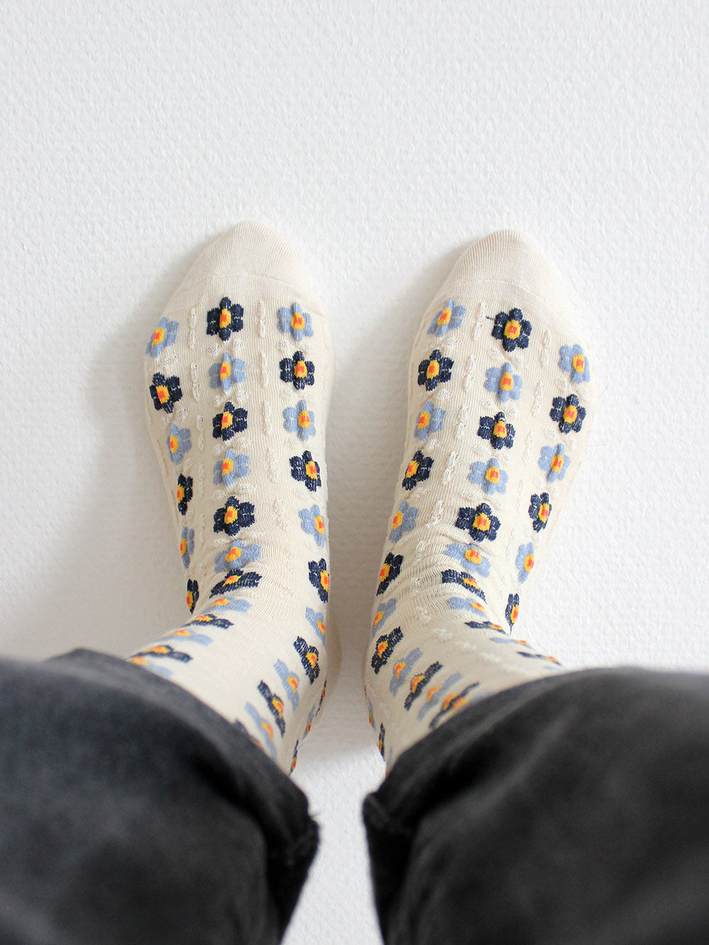 Tragebild von Cremefarbenen Socken mit Stickerei Anmutung und hellblauen und dunkelblauen Blumen mit gelb/roten Blütenstempeln