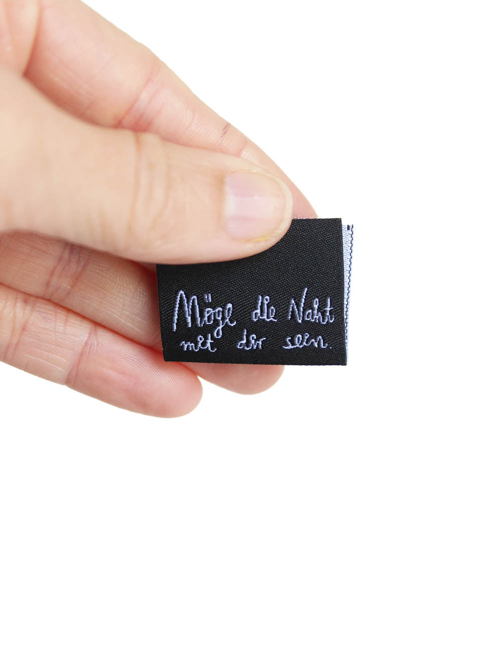 in der Hand gehaltenes Nähetikett aus recyceltem polyester in schwarz mit weißer SChrift möge die naht mit dir sein aus star wars