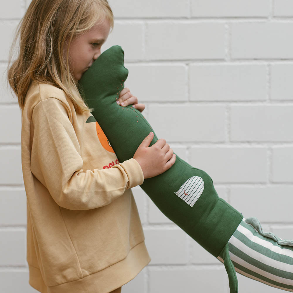 Kind kuschelt mit einer Bettschlange Krokodil in grün