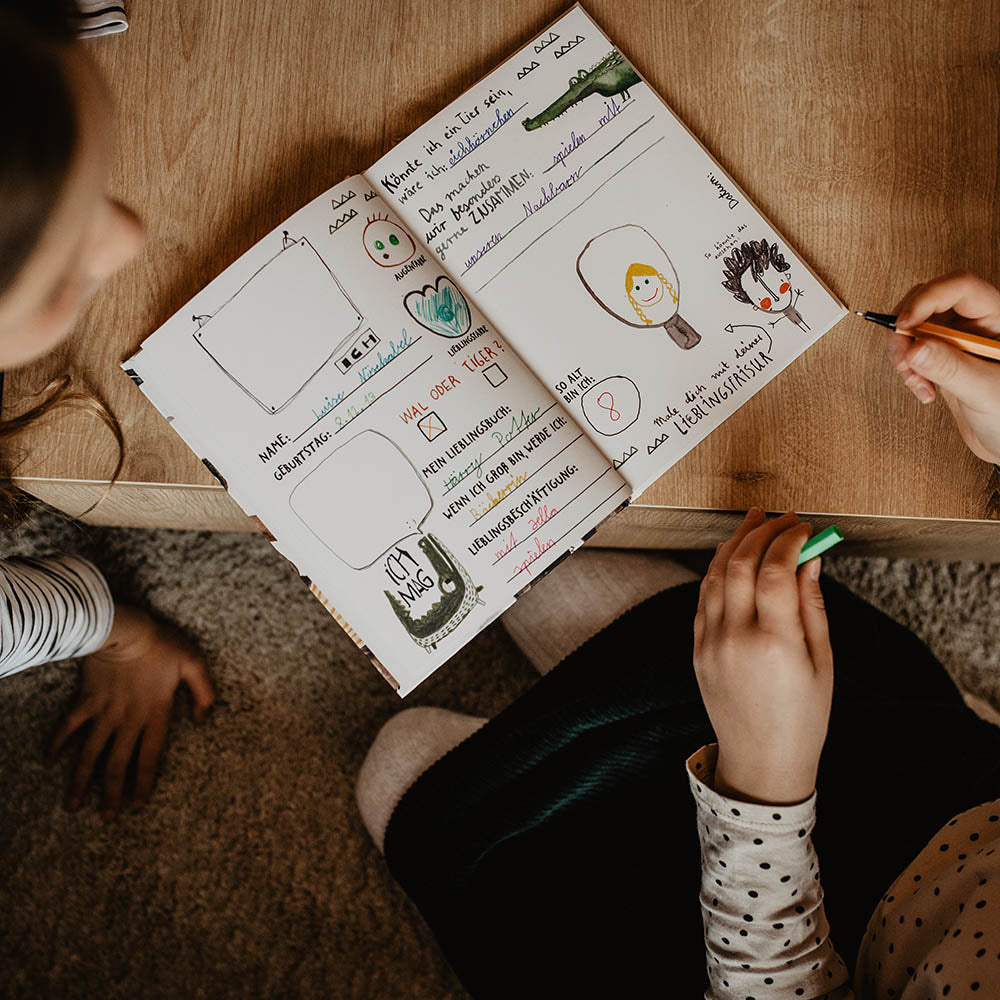 zwei Kinder schreiben in ein Freundebuch