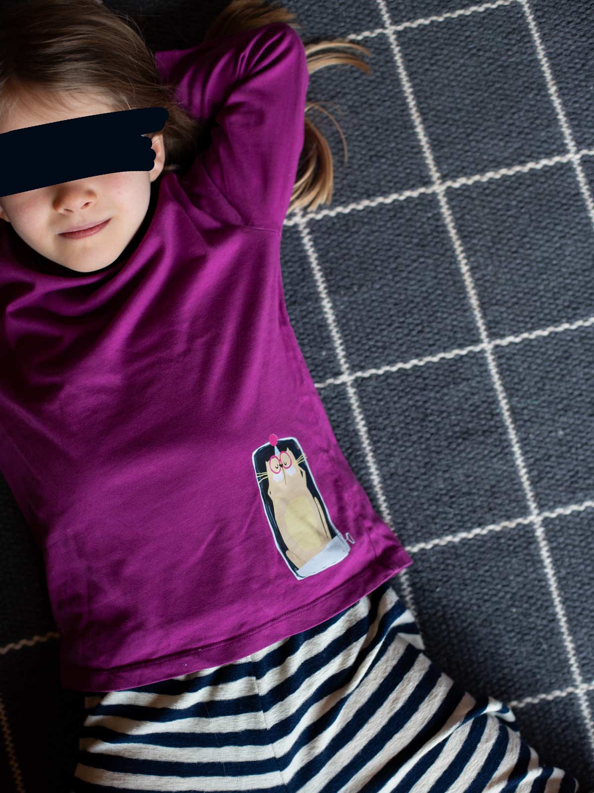 Kind mit himbeerfarbenem Shirt und randlosem Bügelbild "Katze in Sardinendose" von Halfbird