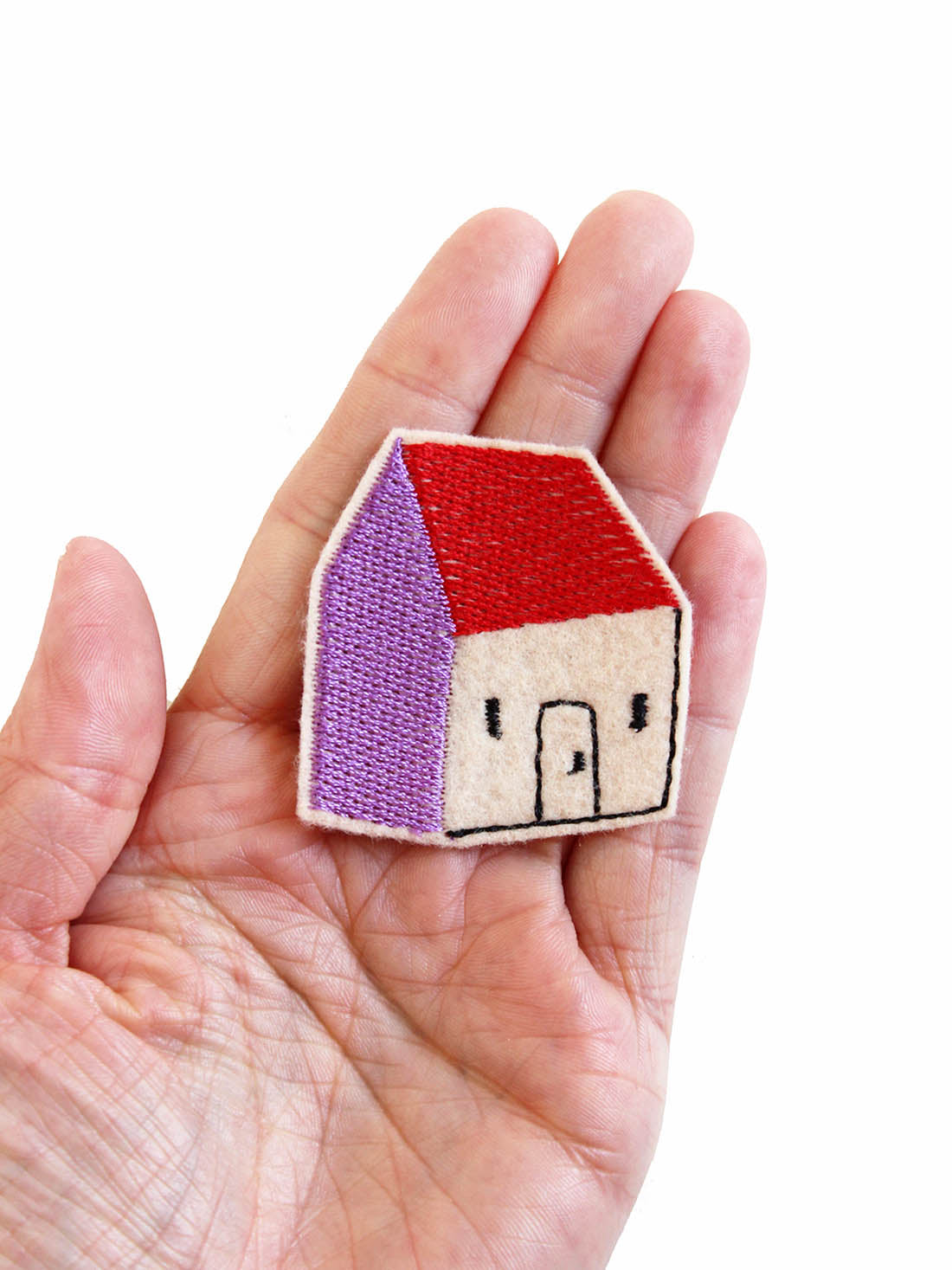 Haus Aufnäher in rot und lila nach einem Design von Donnerstagsonntag auf der Hand liegend