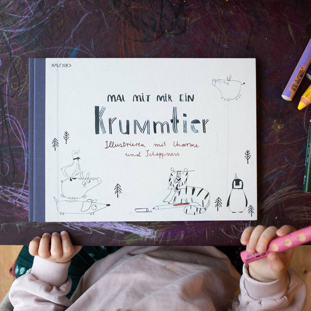 Krummtierbuch von Halfbird auf Kindermaltisch mit Buntstiften