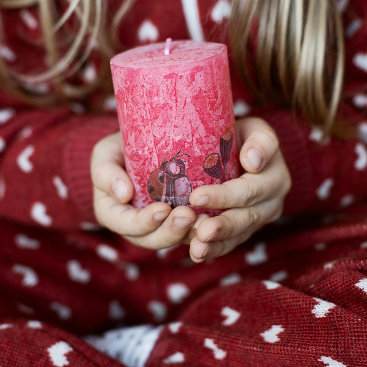 Kind mit roter Kerze in der Hand, die mit Halfbird-Tattoos dekoriert ist