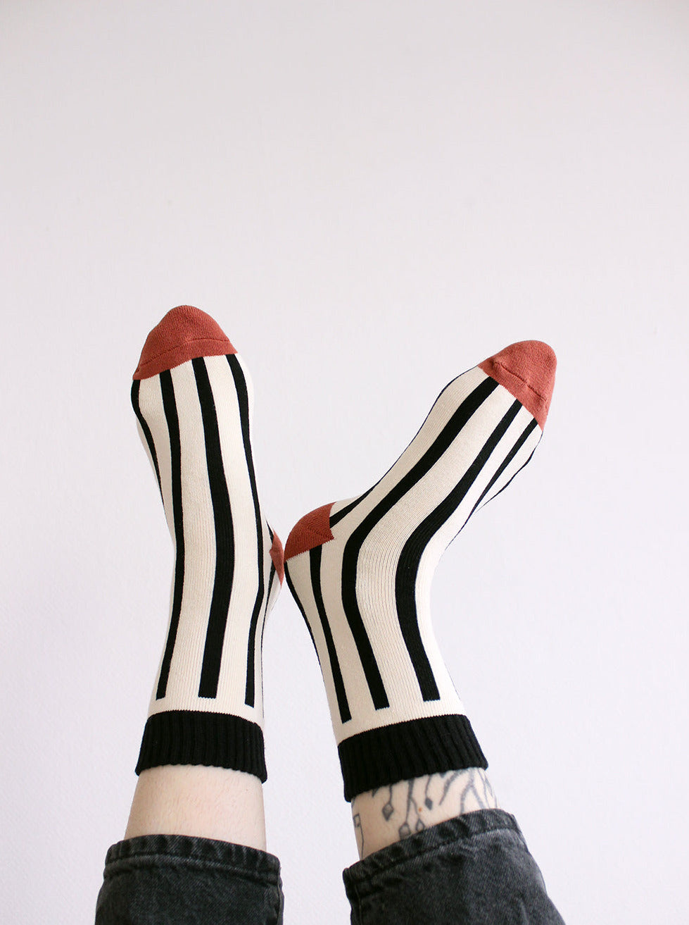 Tragebild von schwarz weiß gestreiften Socken mit rostfarbenem Zwickel und Ferse