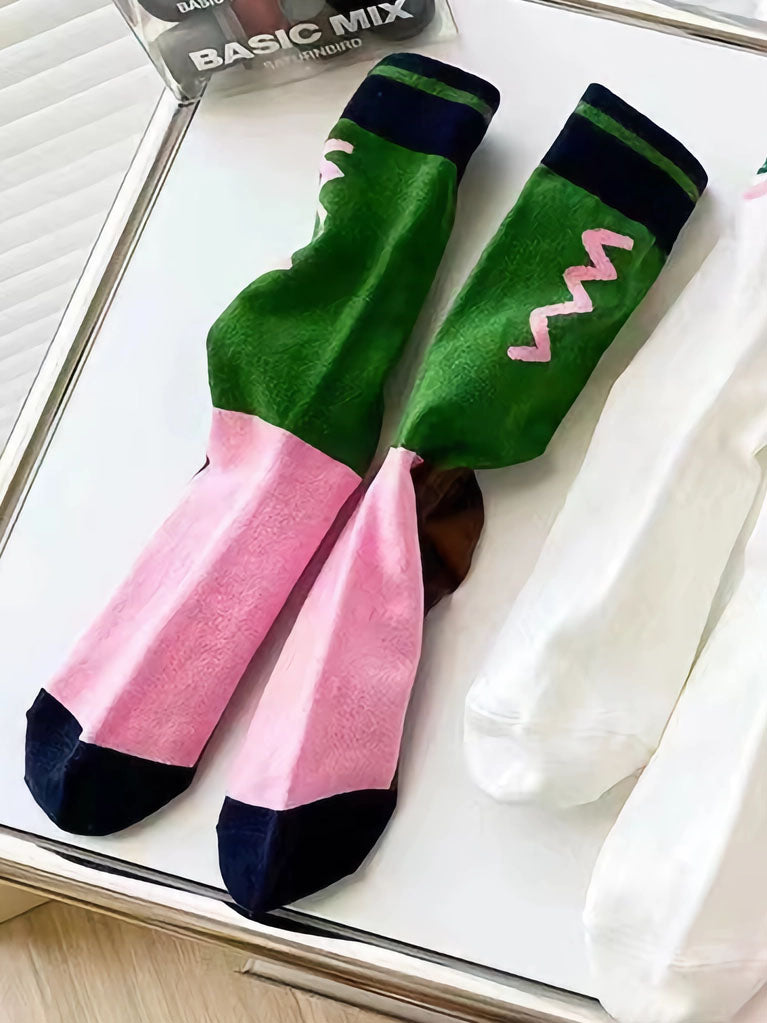 Flatlay von Color Blocking Socken in braun, grün und pink sowie einem geometrischen Muster in der grünen Fläche unterhalb des Bundes