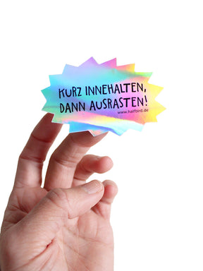 hologramm sticker mit text kurz innehalten, dann ausrasten! von halfbird gehalten von hand