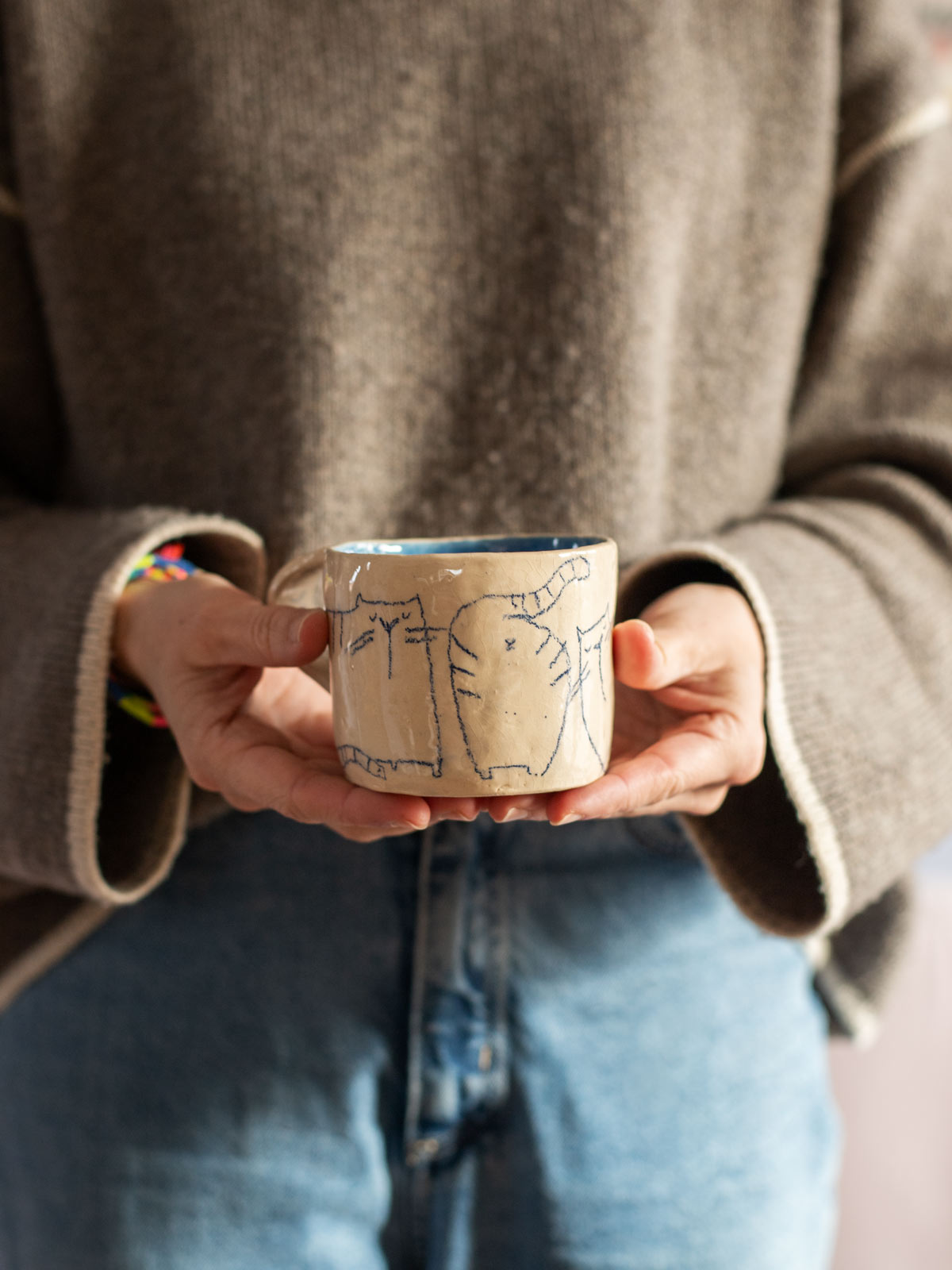 Mona mit Tasse mit Katzenmotiv von Halfbird, aufgemalt mit dem blauen Unterglasurstift von Hobbyceram