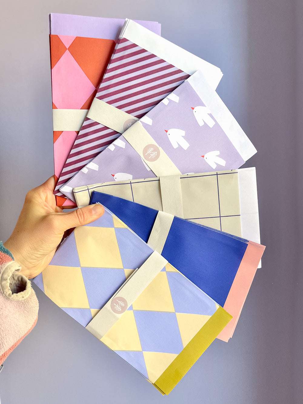 Geschenktüten in verschiedenen Farben und Muster aufgefächert in einer Hand