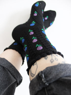 Tragebild schwarze, schlichte Socken mit blau- und rosafarbenen Tulpenblüten mit Strickstruktur