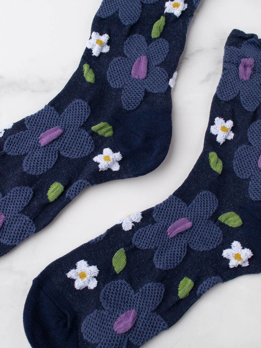 Flatlay Nahansicht Details von dunkelblauen Socken mit erhabener Struktur mit großen taubenblauen und weißen Blumen