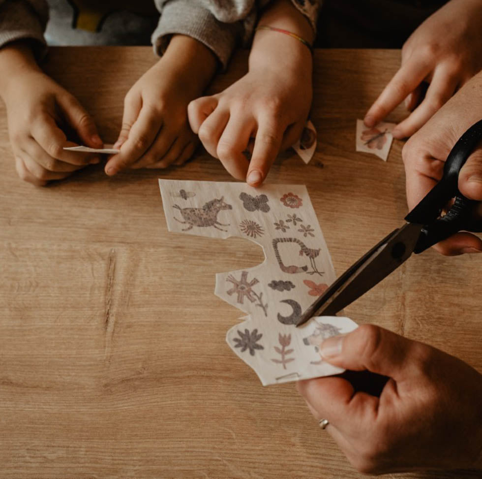 Familie schneidet gemeinsam ein Kindertattoos aus einem Tattoo bogen aus