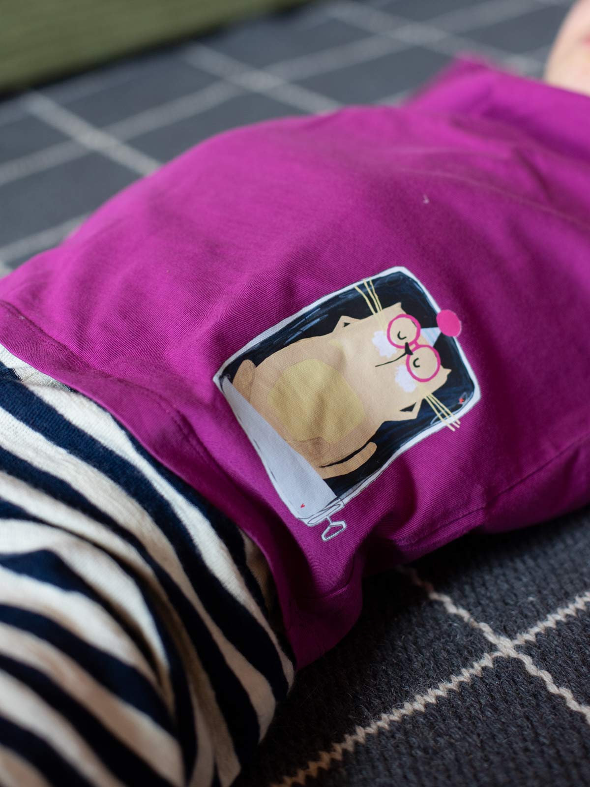 Kind mit himbeerfarbenem Shirt und randlosem Bügelbild "Katze in Sardinendose" von Halfbird