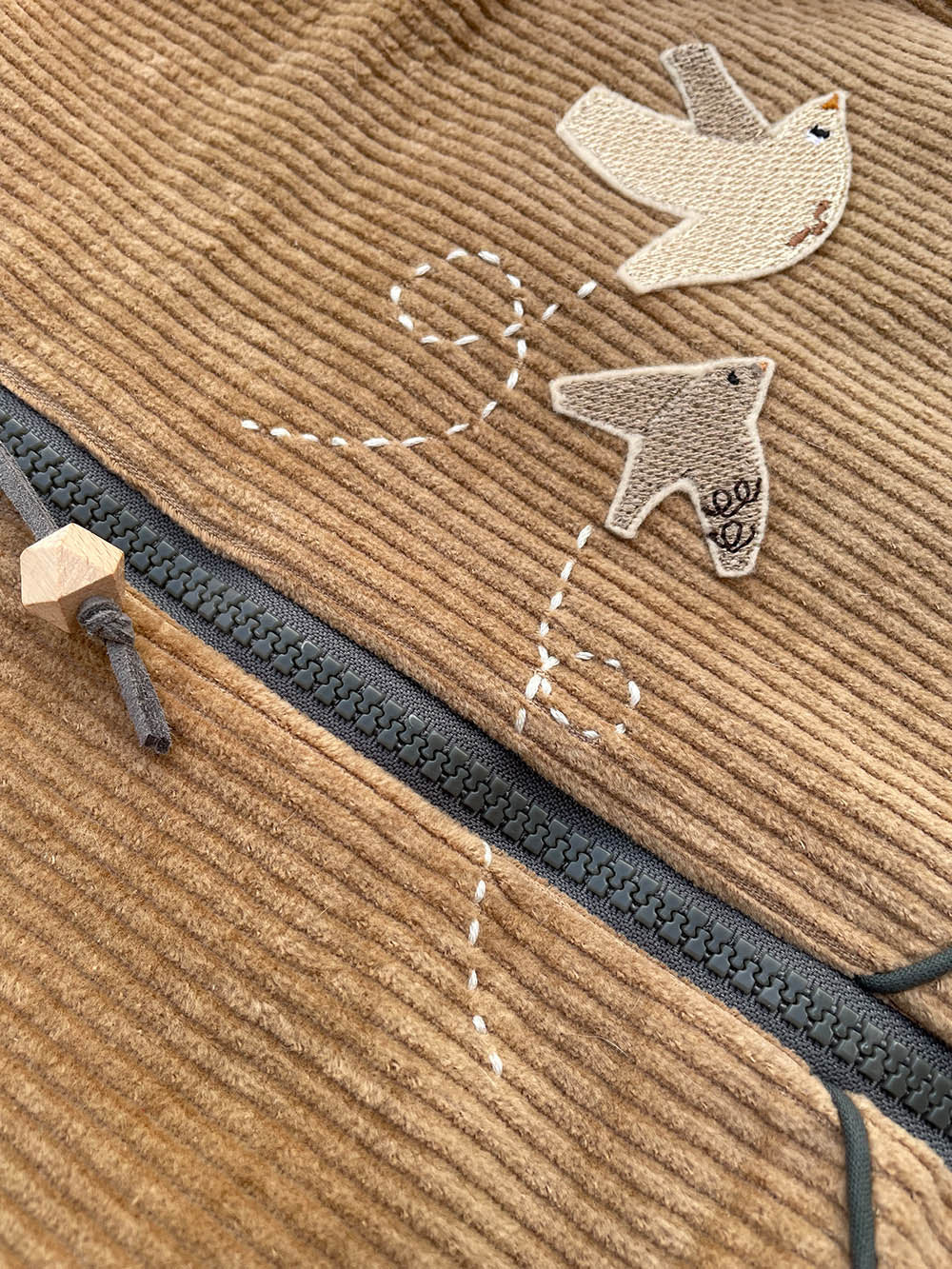 zwei Vogel Aufnäher in beige auf einer Cordjacke mit Stickdetails